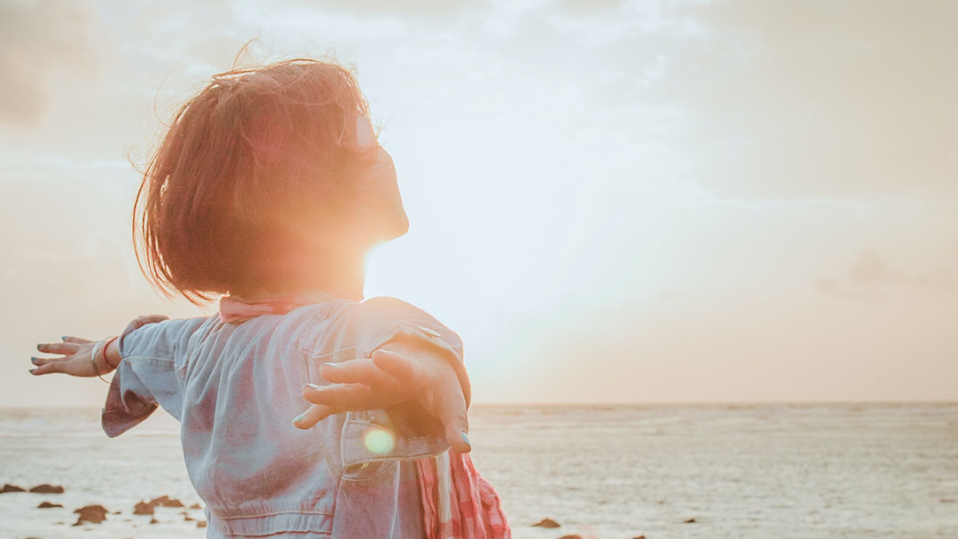 En kvinna står i sin kraft och möter en solnedgång